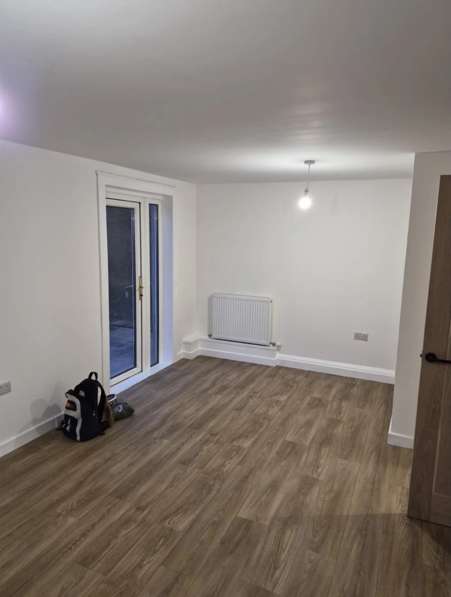 Completed living room with fresh white walls, new wood-effect flooring and new radiator