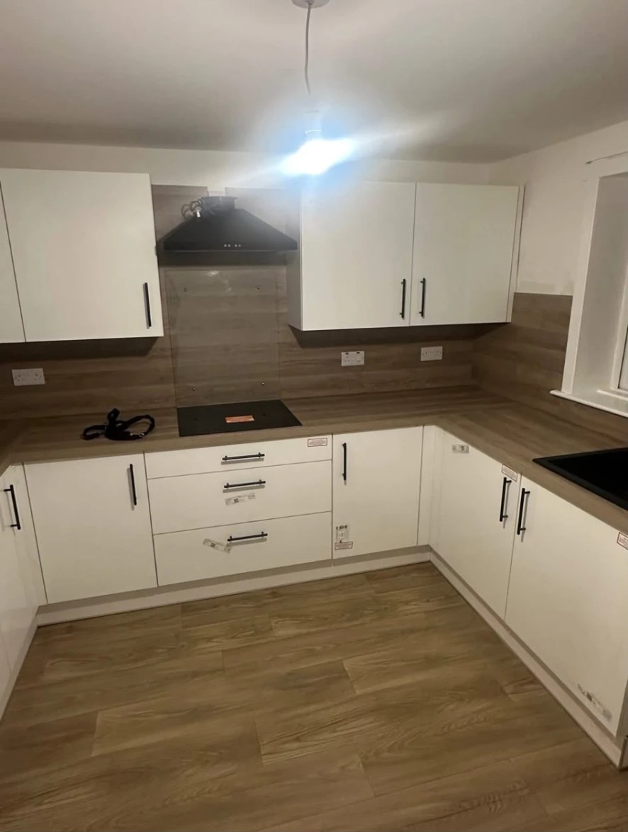 Completed kitchen with white handleless units, wood-effect worktops and new flooring