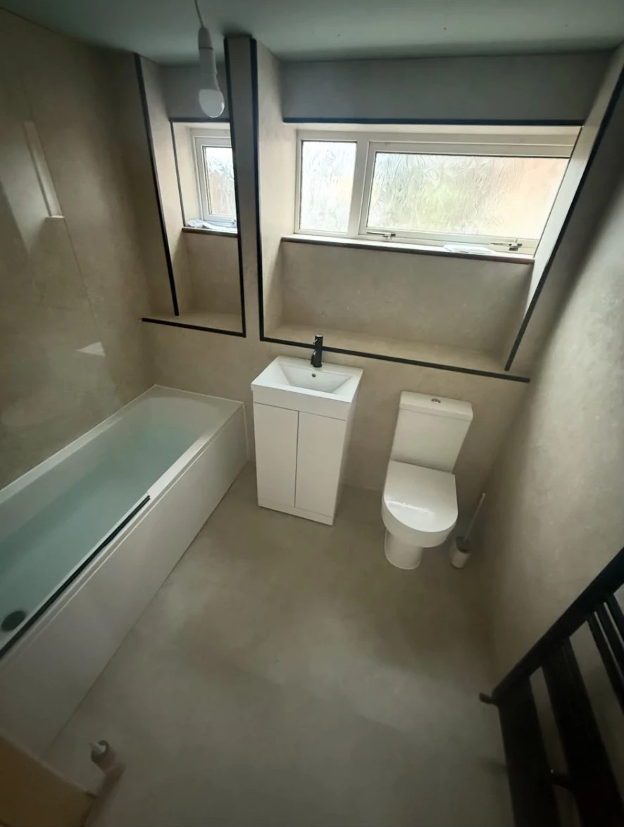 Completed bathroom with new bath, vanity unit and full-height wall panelling