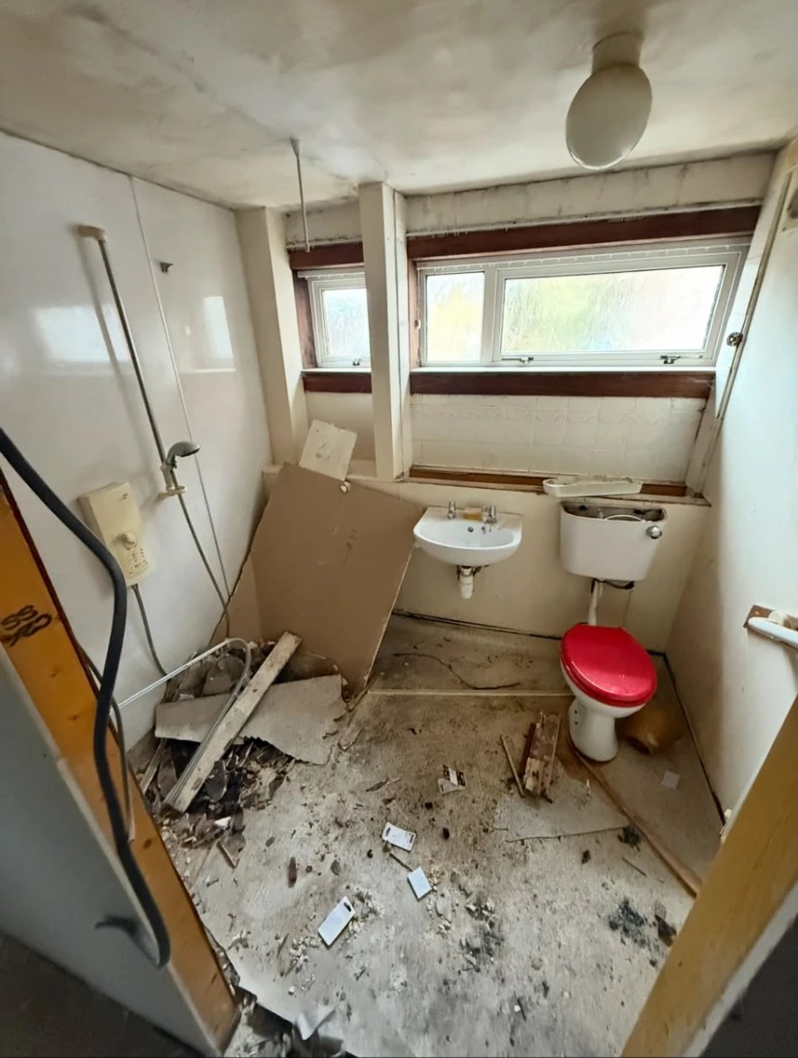 Bathroom before renovation with dated sanitaryware and debris across the floor